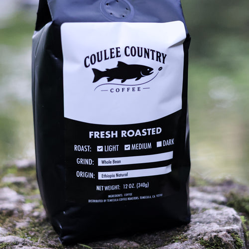 Bag of First Cast Ethiopia natural whole bean coffee on a creekside rock